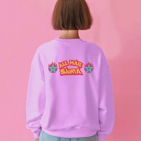 A Christmas sweatshirt featuring a playful design with a cartoon Baphomet goat character wearing a Santa hat. The design includes the text "All Hail Santa" above the goat, with pentagrams in flames on either side. The goat is depicted in a meditative pose, adding a humorous and irreverent twist to holiday attire.
